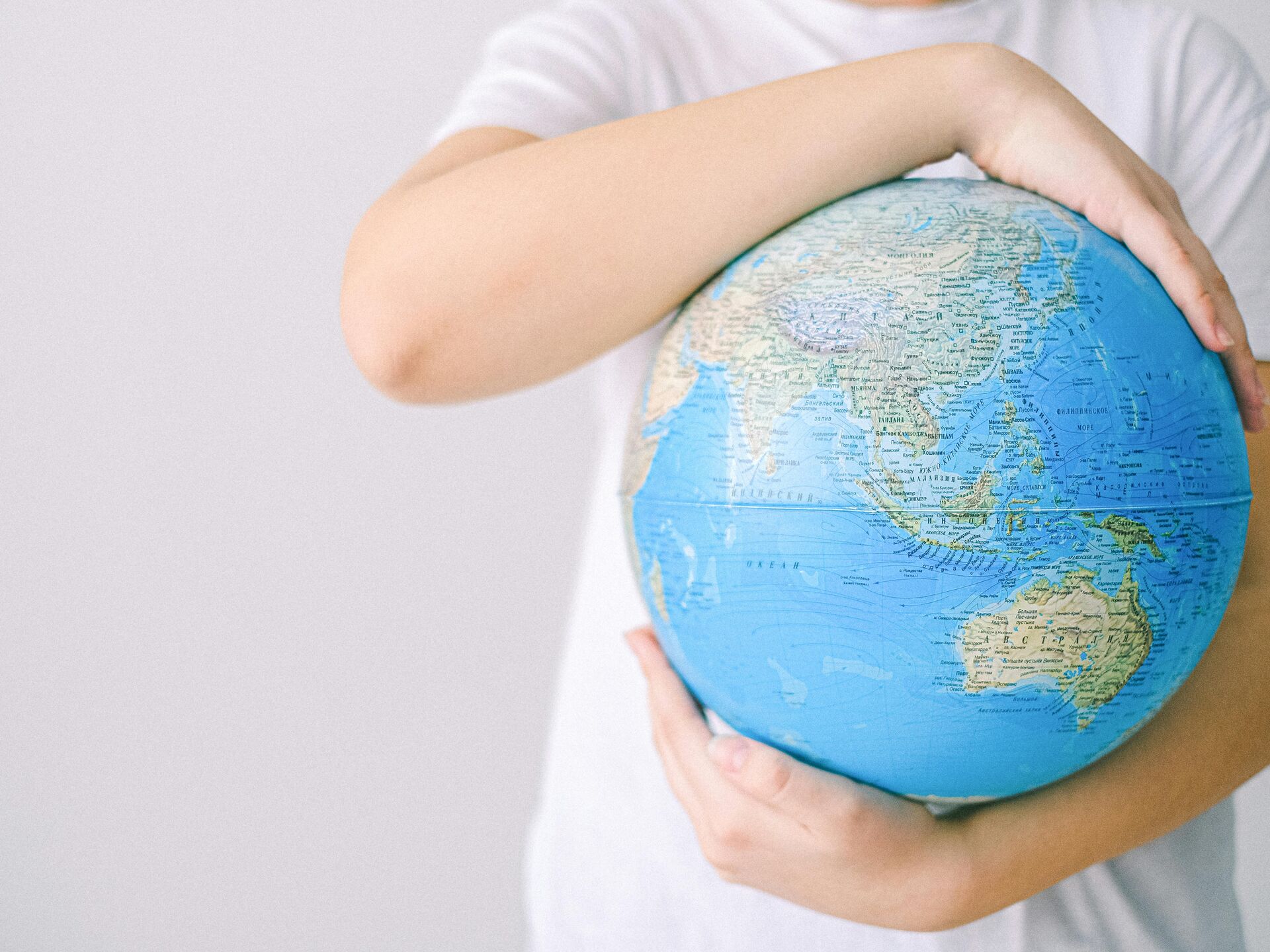 Kind hält einen Globus im Arm, Symbol für Verantwortung und Achtsamkeit gegenüber der Welt.