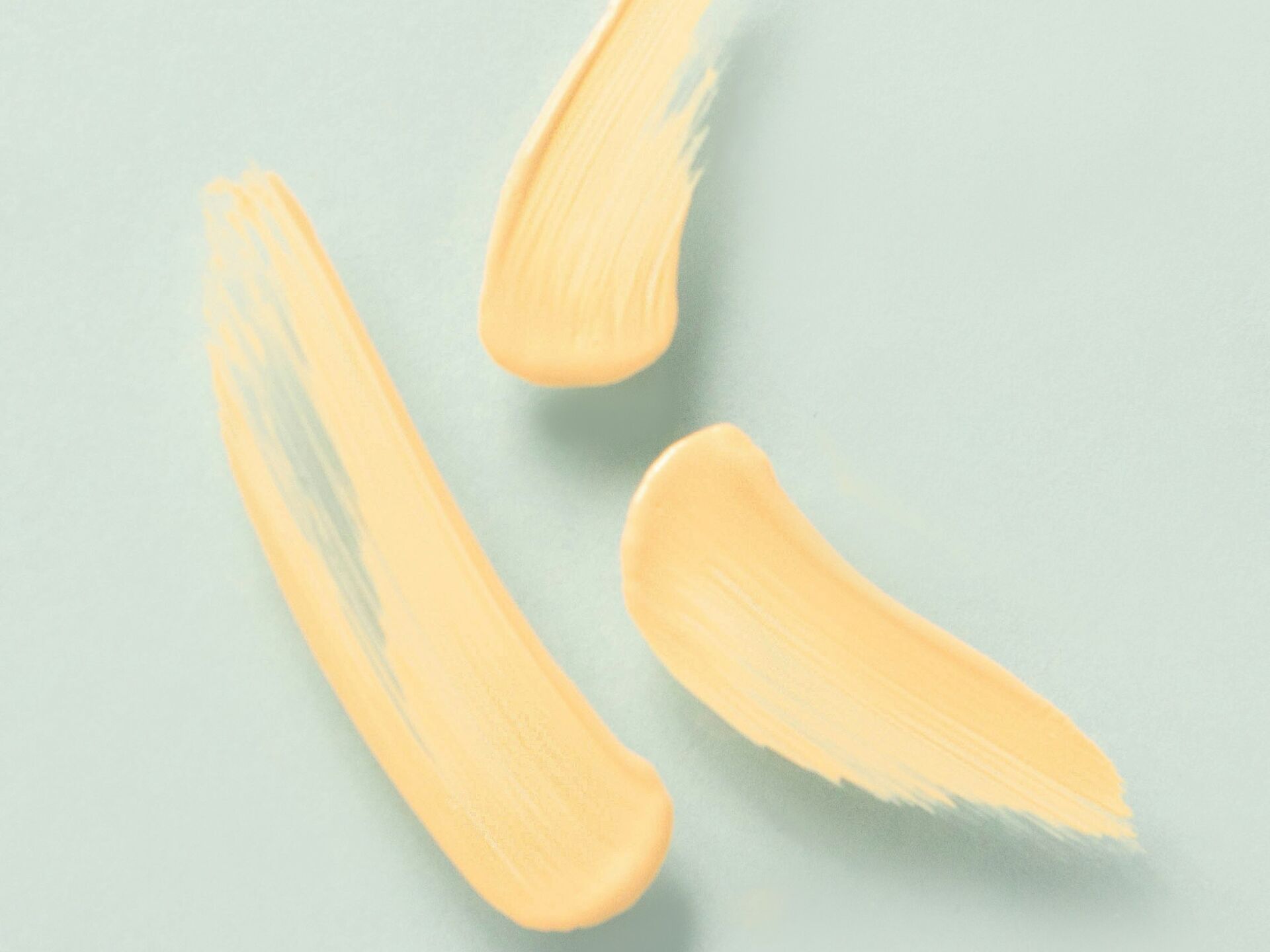 Drei beige Pinselstriche auf hellblauem Hintergrund, minimalistisch arrangiert.