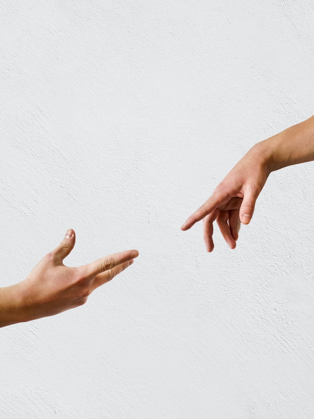 Zwei Hände strecken sich aufeinander zu, vor hellem Hintergrund – Symbol für Verbindung und Unterstützung.