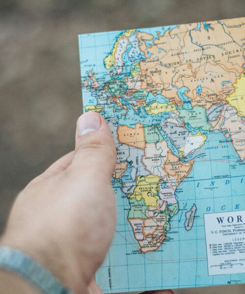 Hand hält eine Weltkarte mit Fokus auf Europa, Afrika und den Nahen Osten.