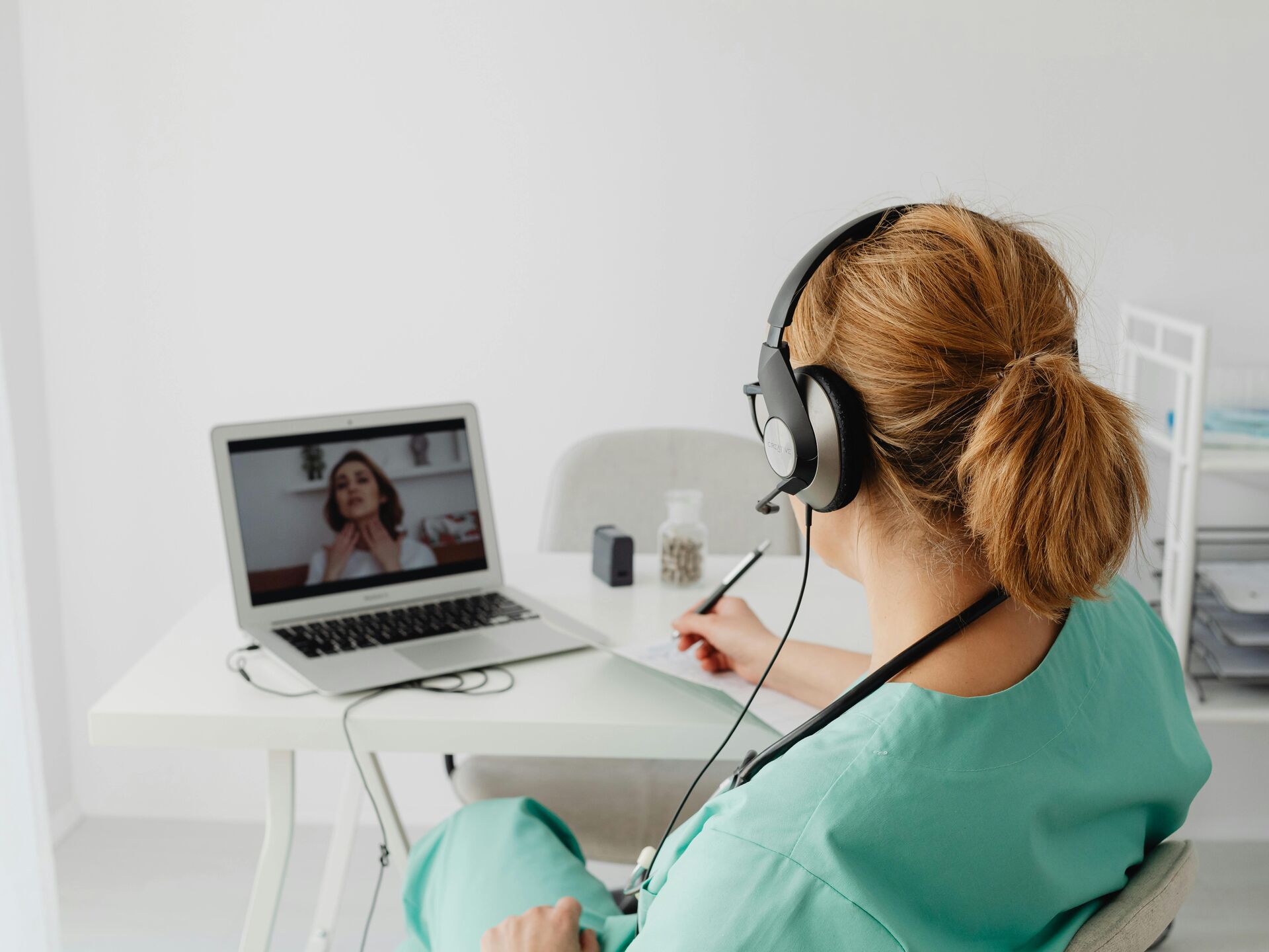 Eine medizinische Fachkraft führt über Laptop und Headset ein Online-Gespräch mit einer Patientin.