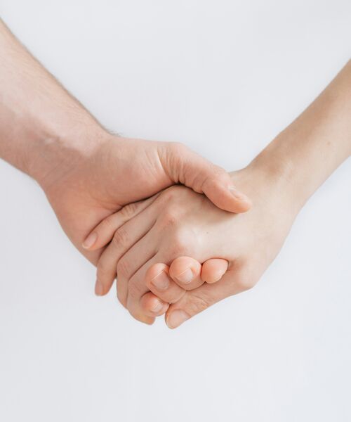Zwei Hände halten sich fest vor hellem Hintergrund – ein Symbol für Vertrauen und Unterstützung.
