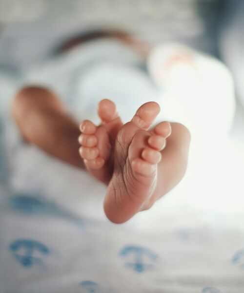 Nahaufnahme der Füße eines neugeborenen Babys auf einer weichen Decke.