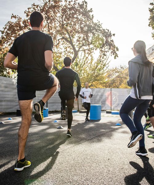 Gruppe von Menschen trainiert gemeinsam im Freien bei sonnigem Wetter.