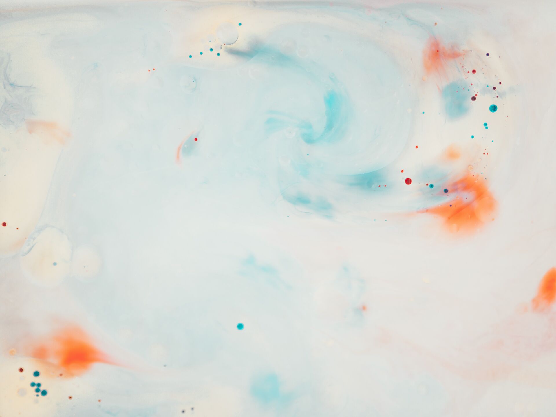 Abstraktes Muster aus sanften Blau- und Orangetönen, die sich wirbelnd auf einer hellen Fläche vermischen.