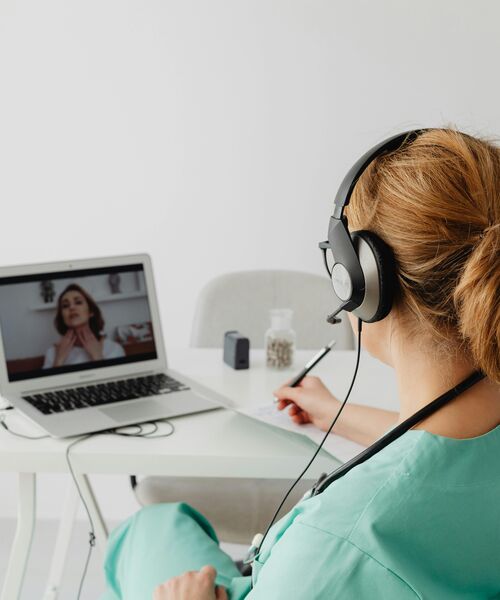 Eine medizinische Fachkraft führt über Laptop und Headset ein Online-Gespräch mit einer Patientin.