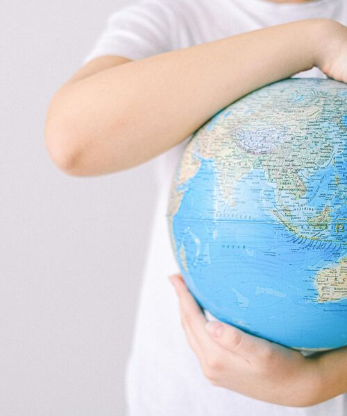 Kind hält einen Globus im Arm, Symbol für Verantwortung und Achtsamkeit gegenüber der Welt.